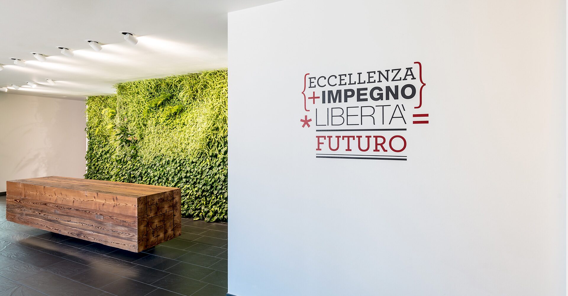 Parete della sede Waldner con il claim Eccellenza + Impegno + Libertà = Futuro